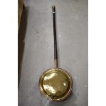 A traditional brass and copper bed warming pan