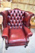 An oxblood red wing back armchair