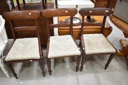 A set of three Victorian rail back dining chairs having later upholstery
