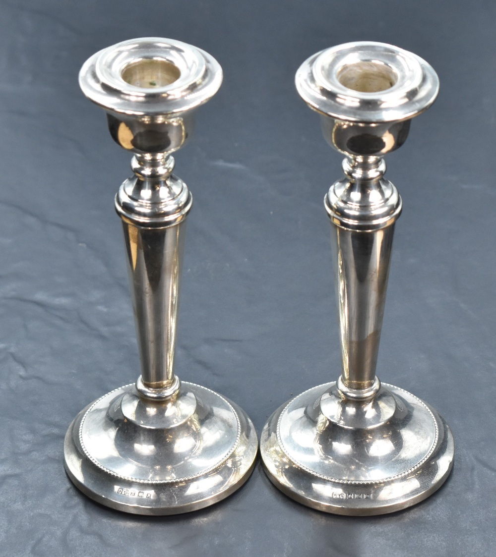 A pair of silver candle sticks of plain tapered form to weighted circular bases, Birmingham 1964,