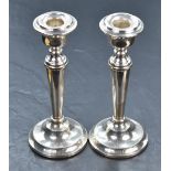 A pair of silver candle sticks of plain tapered form to weighted circular bases, Birmingham 1964,