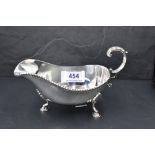 A silver sauce boat having loop handle, gadrooned rim and trefoil hoof feet, Birmingham 1972, Barker