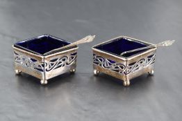 A pair of Edwardian silver salts of diamond form having pierced decoration, blue golass liners and