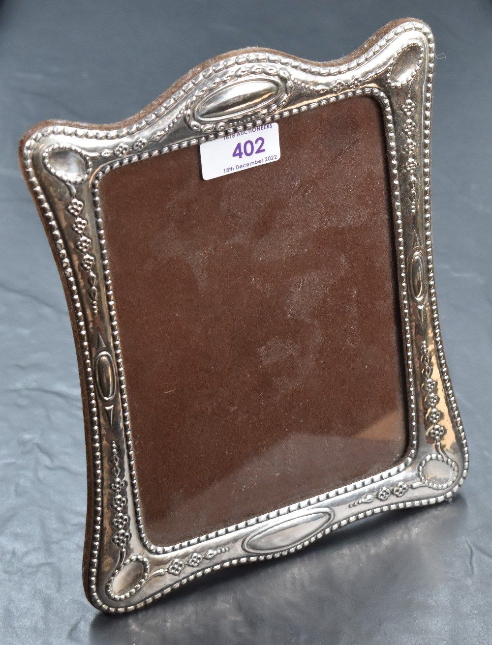 A modern white metal-mounted photograph frame, of traditional design with embossed decoration and