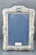 A modern silver photograph frame having moulded scroll decoration with plain cartouche and black