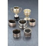 A group of mixed silver items, comprising five napkin rings, silver egg cup and silver trophy with