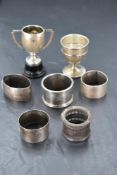 A group of mixed silver items, comprising five napkin rings, silver egg cup and silver trophy with