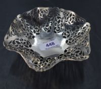 A George V silver dish, of ruffled circular form with repeating pierced decoration, resting on three