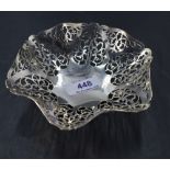 A George V silver dish, of ruffled circular form with repeating pierced decoration, resting on three