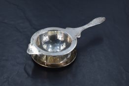 A sterling silver tea strainer with saucer of traditional form by Sammy of Hong Kong, approx 77.3g