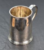 A silver tankard of plain form having moulded handle, reided decoration to lip and foot and engraved