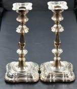 A pair of early 20th Century silver candlesticks of shaped form having removable sconces, shaped