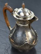 A Victorian silver hot water pot of baluster form having gadrooned decoration, engraved