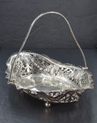 An Edwardian silver table basket of shallow lozenge form having pierced decoration, bun feet and