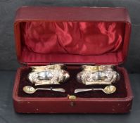 A cased set of Edwardian silver salts, of shaped rectangular form and embossed with foliate scrolls,