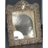 A large Edwardian silver photograph frame having extensive cut decoration, plain cartouche and