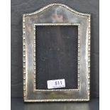 An early 20th Century silver photograph frame of plain arched form with moulded border and wooden