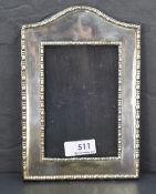 An early 20th Century silver photograph frame of plain arched form with moulded border and wooden