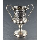 A silver loving cup having loop handles, plain cartouches and gadrooned decoration with pedestal