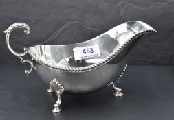 A silver sauce boat having loop handle, gadrooned rim and trefoil hoof feet, Birmingham 1973, Barker