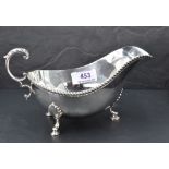 A silver sauce boat having loop handle, gadrooned rim and trefoil hoof feet, Birmingham 1973, Barker