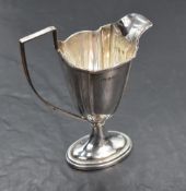 An Edwardian silver cream jug of plain fluted helmet form having reided decoration an