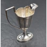 An Edwardian silver cream jug of plain fluted helmet form having reided decoration an