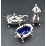 A silver three piece cruet set of traditional form having blue glass liners and paw feet, Birmingham