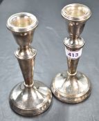 A pair of silver candlesticks of plain form having tapered stems and circular weighted bases,