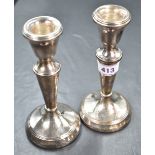 A pair of silver candlesticks of plain form having tapered stems and circular weighted bases,