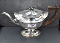 A small Edwardian silver teapot of plain shaped form on pedestal foot with Architectural wooden