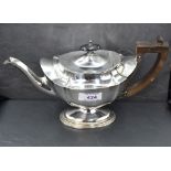 A small Edwardian silver teapot of plain shaped form on pedestal foot with Architectural wooden