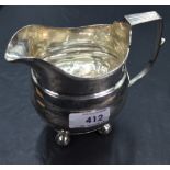 A Georgian silver cream jug of plain form having bun feet and archictural handle, Newcastle 1815,