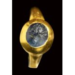 A late roman blue sapphire intaglio set in a gold ring. Peacock. 4th century A.D.