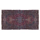 A LARGE PERSIAN RED GROUND WOOL CARPET, mid-20th Century, woven to the centre with a large