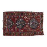 A PERSIAN RED GROUND WOOL CARPET, of rectangular shape woven with three large medallions and