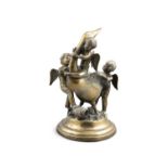 A BRASS GROUP OF A DUCK WITH WINGED PUTTI ON A HEAVY CIRCULAR BASE. 37cm high