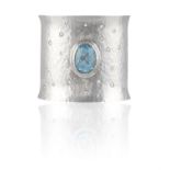 A TOPAZ AND DIAMOND CUFF BRACELET, the hammered silver cuff centring an oval-shaped blue topaz
