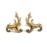 A PAIR OF FRENCH GILT BRONZE CHENETS, early 19th Century, modelled as scroll leaves in the Rococo