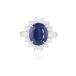 A SAPPHIRE AND DIAMOND CLUSTER RING The oval-shaped sapphire weighing approximately 5.