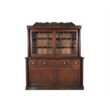 A WILLIAM IV MAHOGANY TWO-DOOR BOOKCASE, surmounted with carved foliate cresting above twin glazed