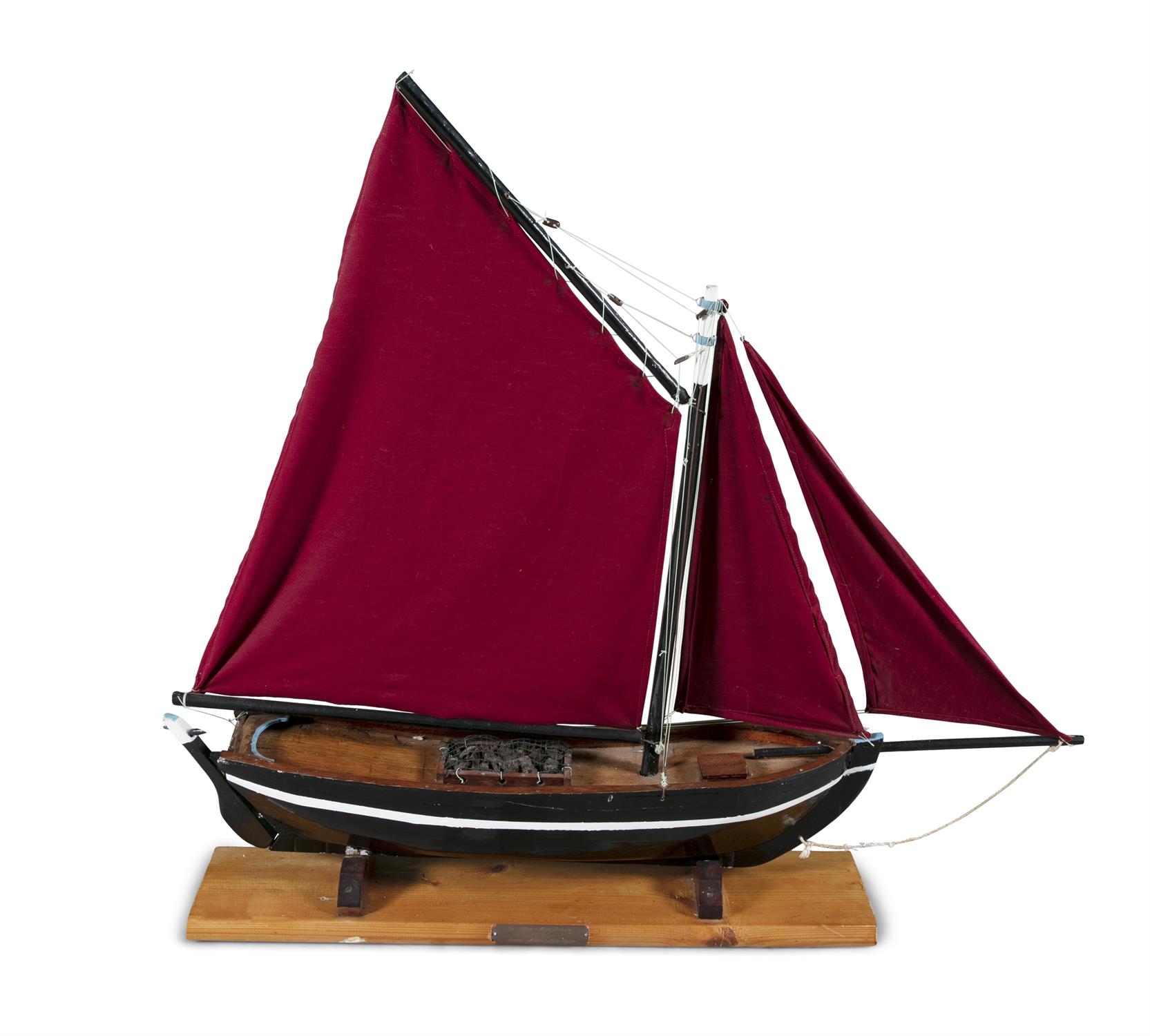 A PAINTED TIMBER MODEL OF A GALWAY HOOKER, with traditional red sails, on a timber stand.