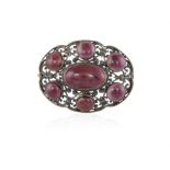 AN EARLY 20TH CENTURY GARNET BROOCH, of openwork design set with garnet cabochons within scrolling