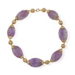 AN AMETHYST BEAD NECKLACE, composed of large carved amethyst beads with gold caps and interspersed