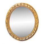 AN OVAL GILDED MIRROR, with plain glass plate, bordered with a continuous row of applied spheres.