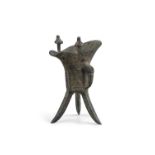 AN ARCHAISTIC BRONZE TRIPOD WINE VESSEL, JUE CHINA, QING DYNASTY, AFTER A SHANG DYNASTY MODEL