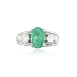 AN EMERALD AND DIAMOND RING Set with an oval emerald cabochon with graduated brilliant-cut