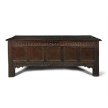 A LARGE 17TH CENTURY OAK COFFER, with solid hinged rectangular top above five panelled frieze