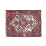 A NAHAVAND RED GROUND RUG, Iran, the central field woven with three interlocking lozenges within a