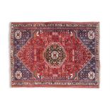 A KASHGAI / QASHQAI RED GROUD WOOL RUG, the central field woven with a large flowerhead medallion